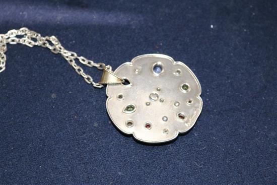 A bespoke white metal and multi gem set shaped circular pendant, on a white metal chain, pendant 52mm.